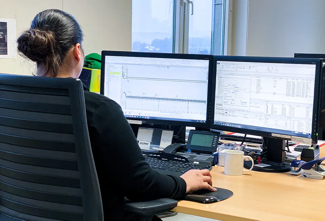 Frau am Schreibtisch mit Blick auf 2 Bildschirme